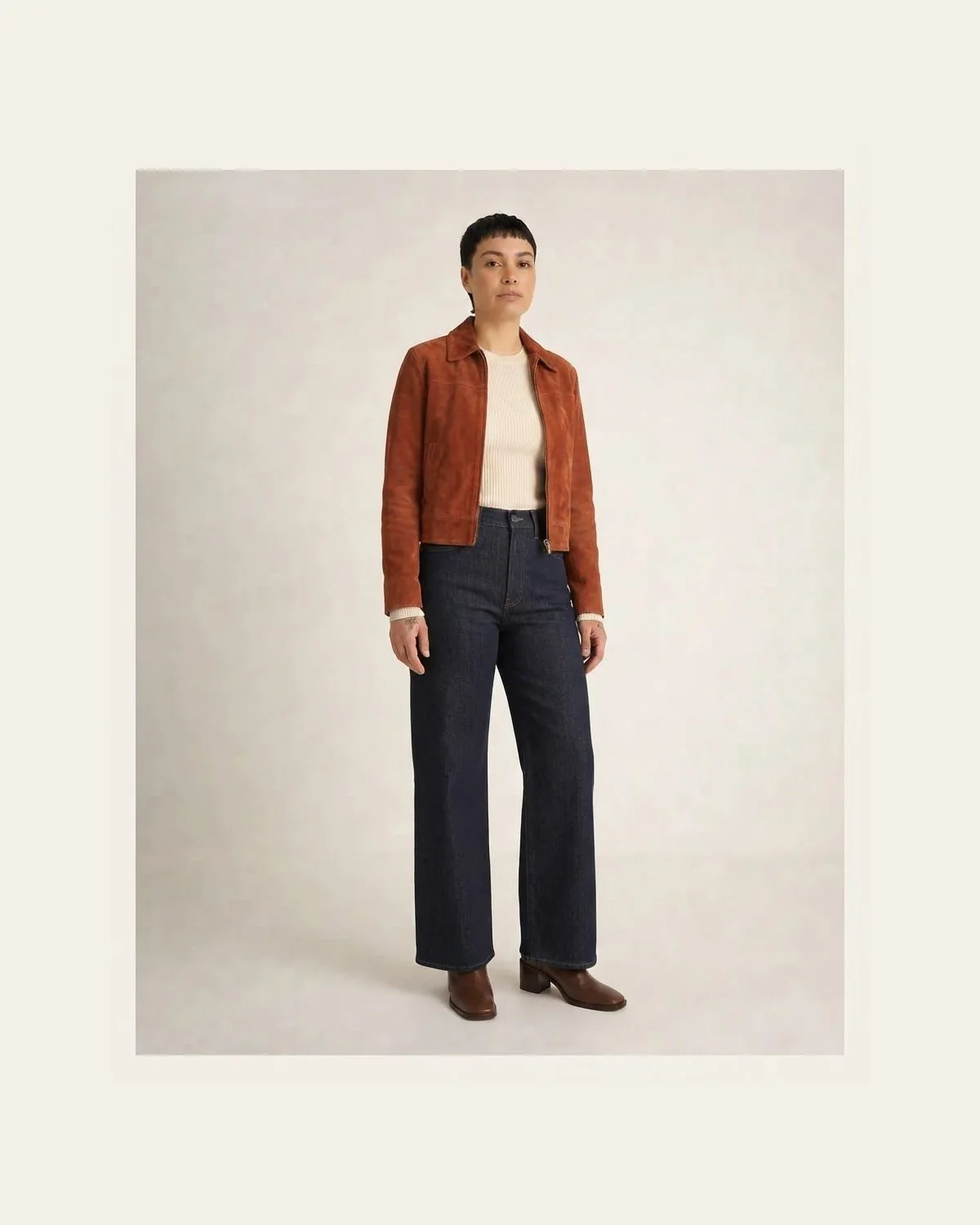 Rust jacket, cream knit, dark wide-leg jeans, and ankle boots