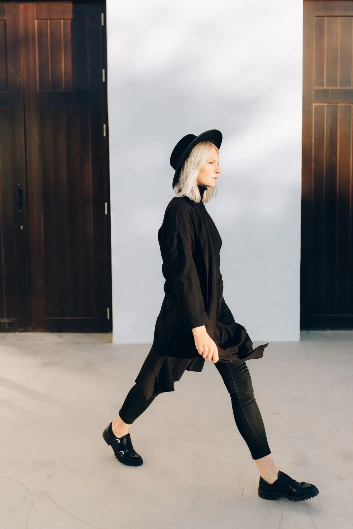 Long black coat with black hat, leggings, and loafers