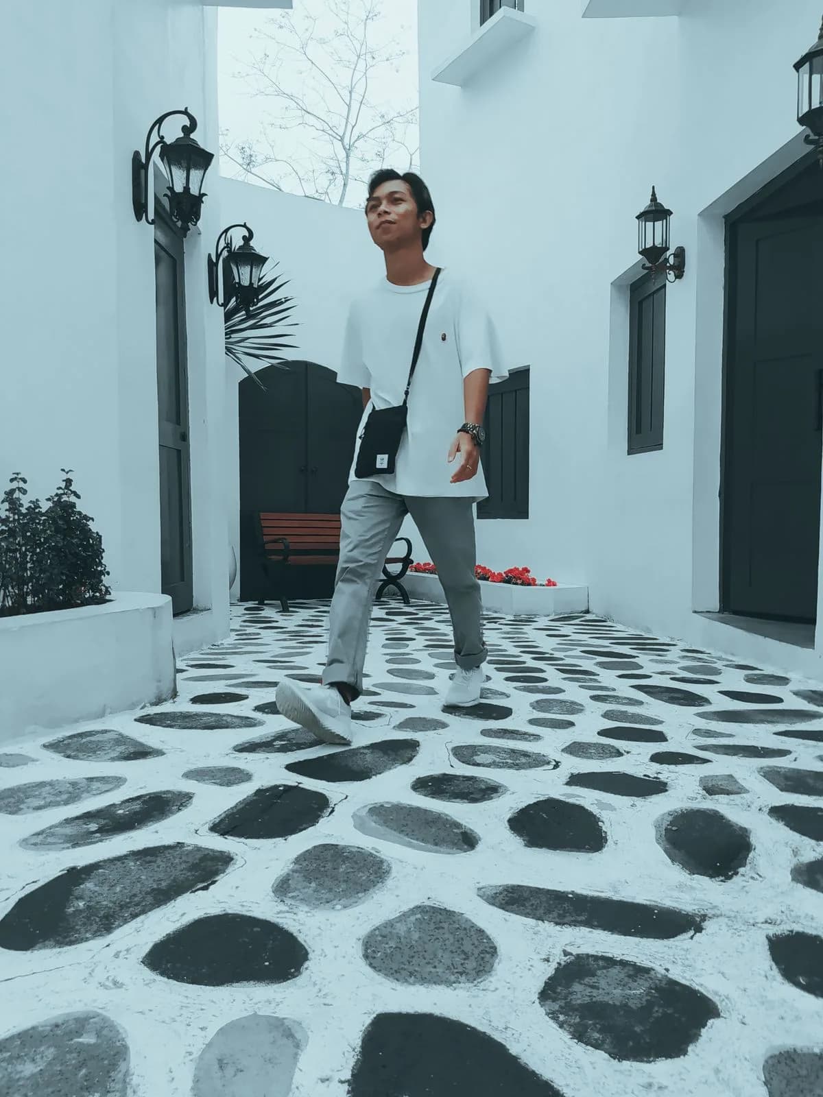 White T-shirt with gray trousers and crossbody bag on a bright street