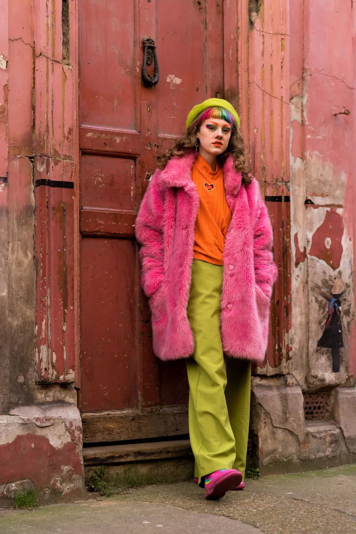 Hot pink faux-fur coat with orange top and chartreuse trousers