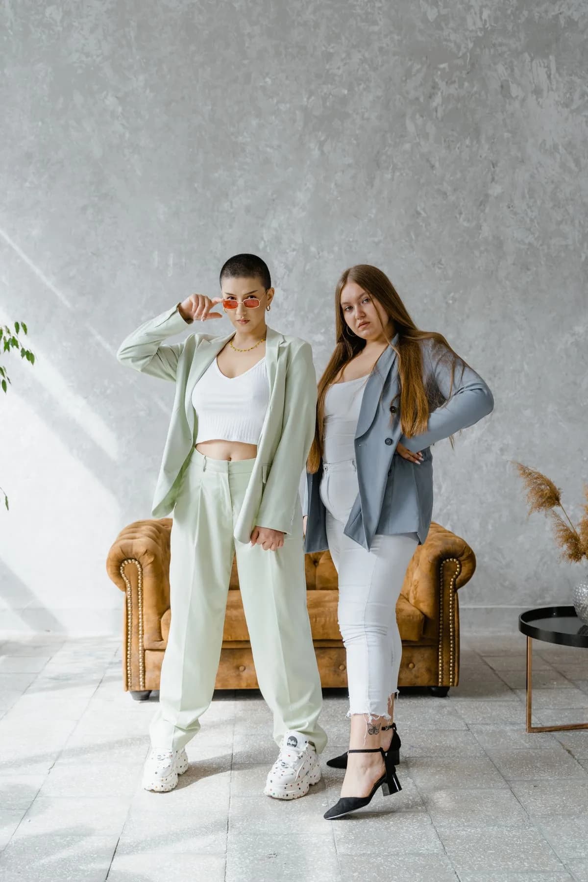 Two plus-size women wearing soft green and gray tailored outfits