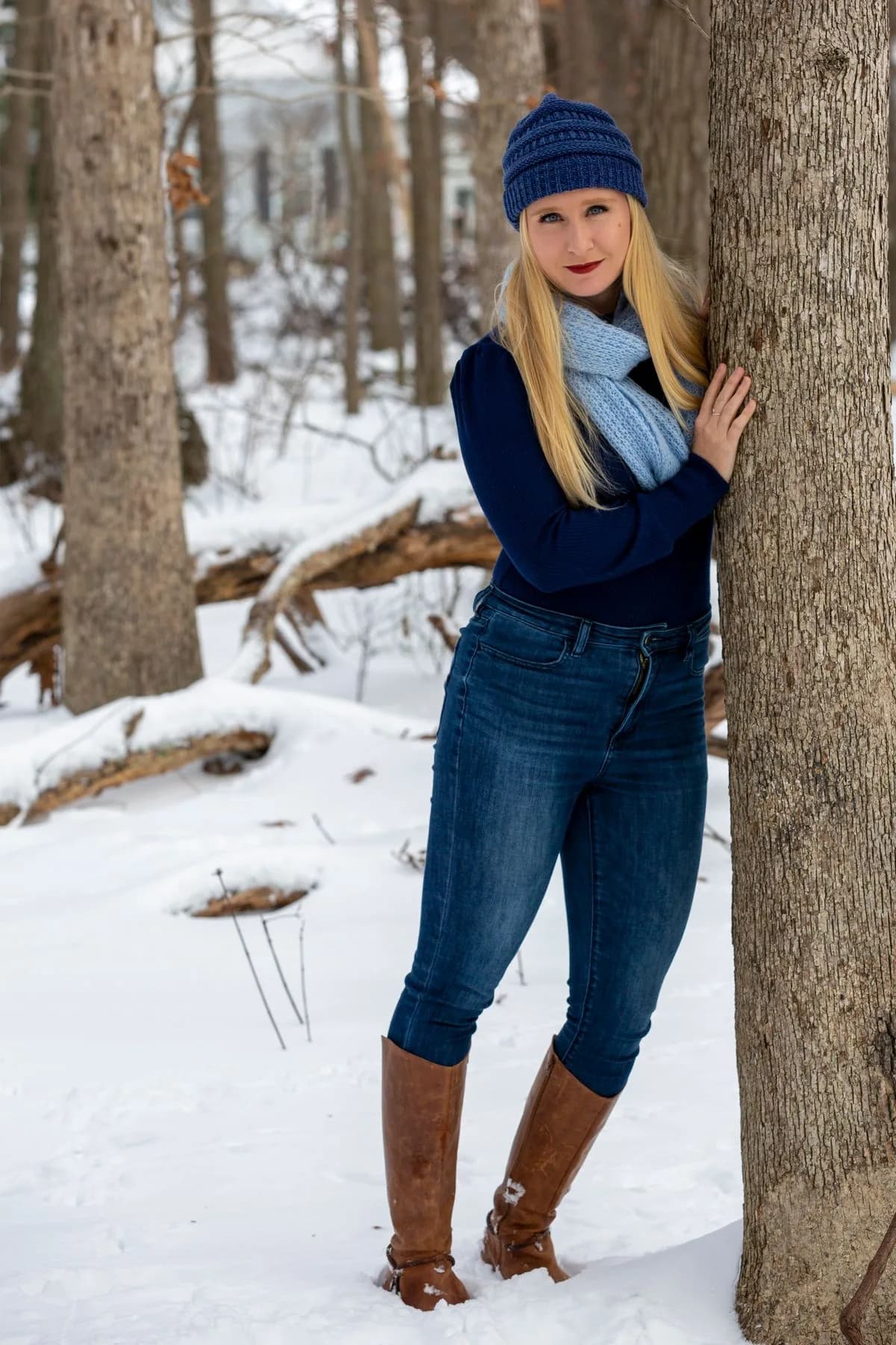 Navy sweater with blue scarf, jeans, brown boots, and knit hat